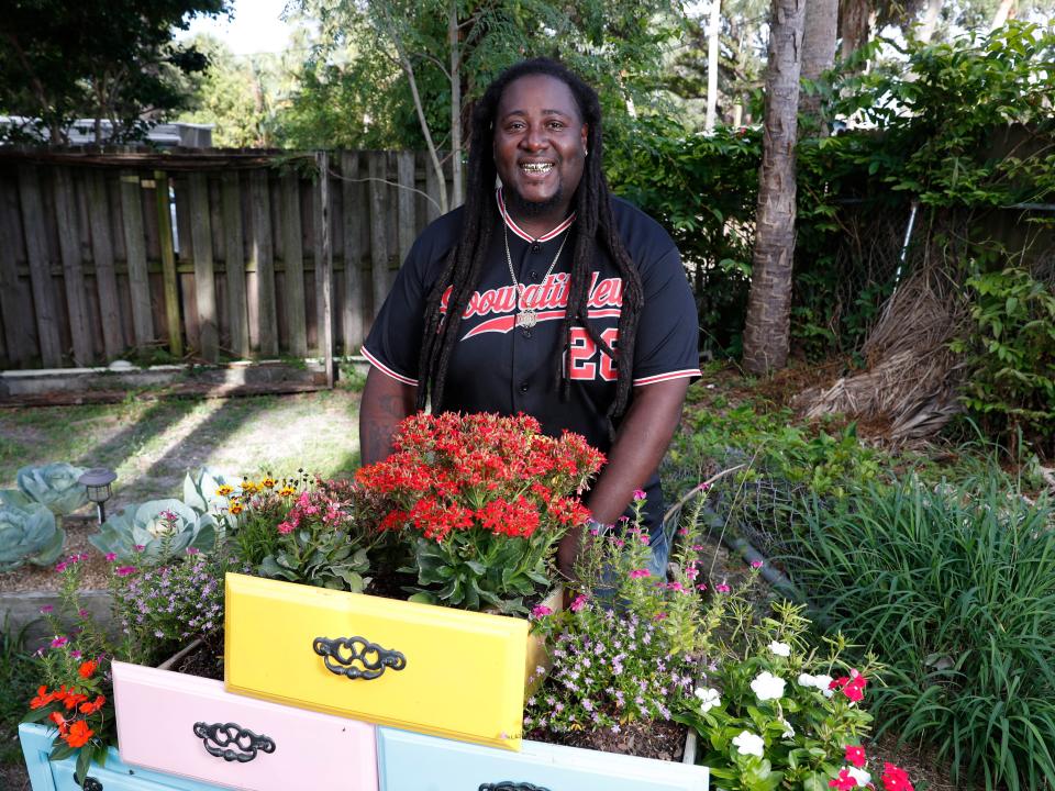 Corey "Goo" Paul wears a jersey and smiles while standing in his garden.