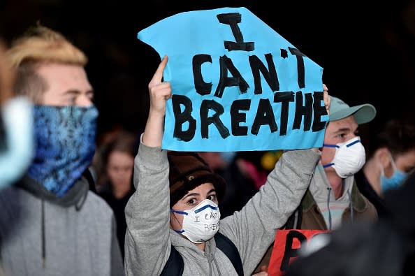 A protester wearing a face mask holds up a sign reading, 'I can't breathe', during a Sydney rally.