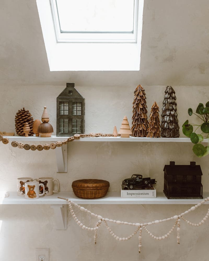 Open white wall shelves with wooden Christmas garlands