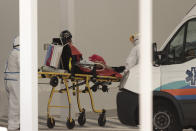 A patient infected with the new coronavirus is transferred from an ambulance onto a stretcher at the emergency entrance of the National Hospital in San Salvador, El Salvador, Friday, Aug. 7, 2020. For months, the strictest measures confronting the COVID-19 pandemic in Latin America seemed to keep infections in check, in El Salvador, but a gradual reopening combined with a political stalemate has seen infections increase nearly fourfold ny August. (AP Photo/Salvador Melendez)