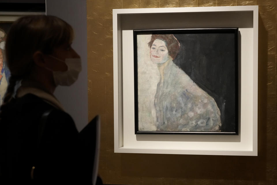 A woman admires Gustav Klimt's oil on canvas painting "Portrait of a Lady in White" (1917/18) on display at the exhibition "Klimt. The Secession and Italy" at the Museum of Rome, in Palazzo Braschi, Rome, during a press preview, Tuesday, Oct. 26, 2021. The exhibition, that explores Klimt's period in Italy, will be open to visitors from Oct.27, 2021 to March 27, 2022. (AP Photo/Andrew Medichini)