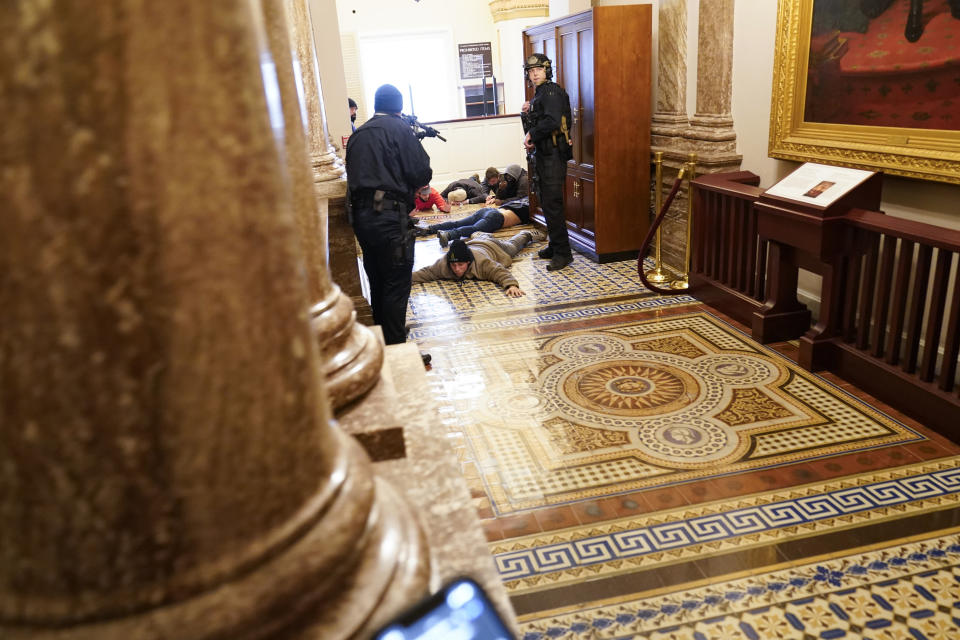 FILE - In this Jan. 6, 2021, file photo U.S. Capitol Police hold insurrectionists loyal to President Donald Trump at gun-point near the House Chamber inside the U.S. Capitol in Washington. A month ago, the U.S. Capitol was besieged by Trump supporters angry about the former president's loss. While lawmakers inside voted to affirm President Joe Biden's win, they marched to the building and broke inside. (AP Photo/Andrew Harnik, File)