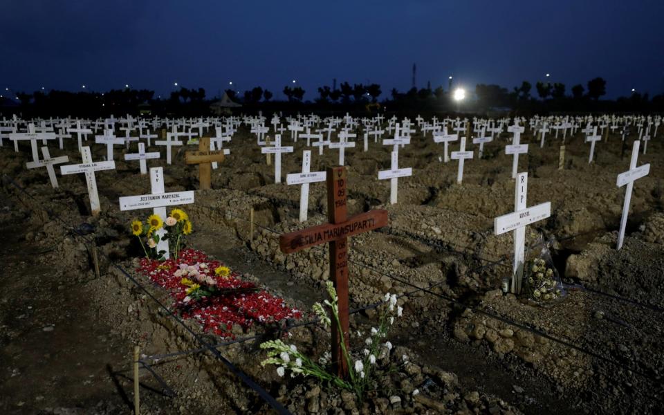 Flowers are left on graves at a burial area provided by the government for coronavirus disease victims in Jakarta, Indonesia - Reuters