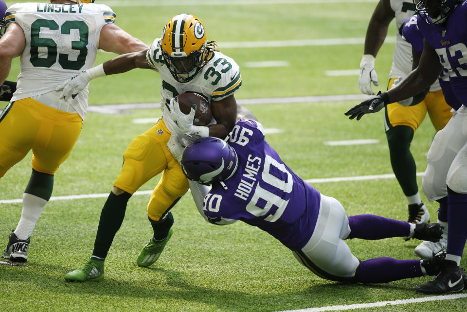 Green Bay Packers running back Aaron Jones (33) tries to break a tackle by Minnesota Vikings defensive tackle Jalyn Holmes during the first half of an NFL football game, Sunday, Sept. 13, 2020, in Minneapolis. (AP Photo/Bruce Kluckhohn)