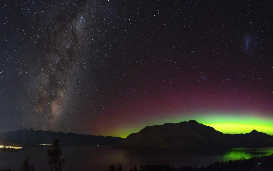 Spectacular view as aurora and milky way galaxy lights up the sky. When particles from a solar storm reached our Earth, it creates an array of colored lights as they hit the atmosphere - Shutterstock