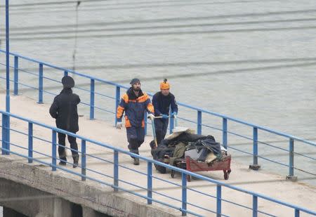 Russian Emergencies Ministry members push a cart with remains of Russian military Tu-154 plane which crashed into the Black Sea, at a quay in the Sochi suburb of Khosta, Russia, Russia December 25, 2016. REUTERS/Yevgeny Reutov