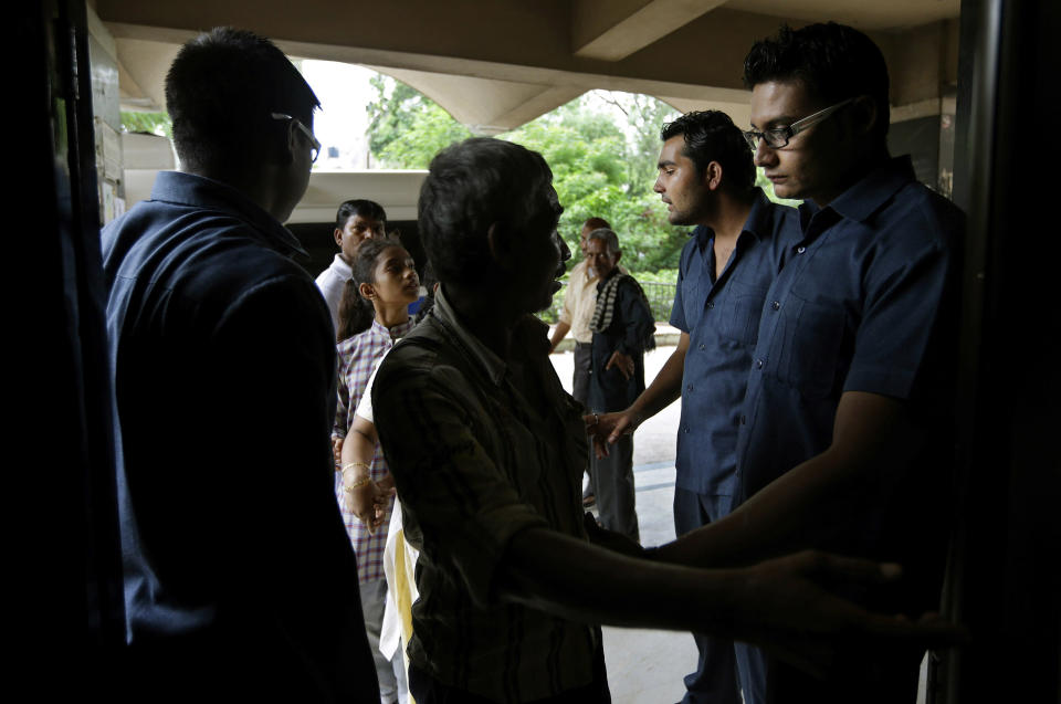 In this Tuesday, Aug. 21, 2012 photo, Pradeep Kumar, left and another security guard frisk incoming patients at the Deen Dayal Upadhyay Hospital in New Delhi, India. Kumar and 20 other bouncers have been hired to protect doctors as well as keep the emergency and labor rooms from filling up with patients’ often agitated relatives and friends. (AP Photo/Saurabh Das)