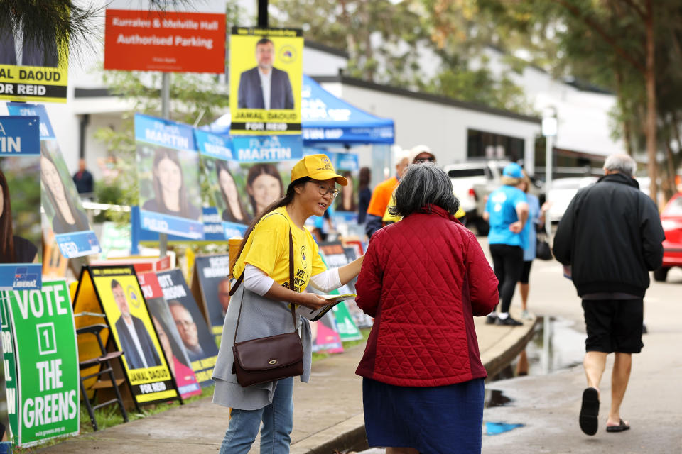 Volunteers hand out voting information leaflets to people as they arrive at a voting centre.