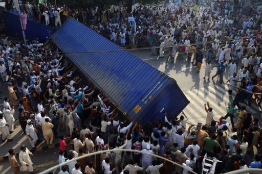 Pakistani Muslim demonstrators topple a freight container, placed by police to block a street, during a protest against an anti-Islam film in Lahore. Violent demonstrations in Pakistan left at least 17 people dead and hundreds injured as fresh protests erupted across the Muslim world against a US-made film and French cartoons mocking Islam