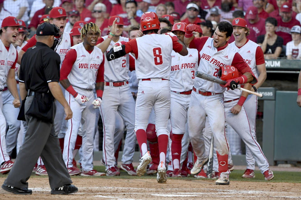 North Carolina State's Jose Torres (8) is greeted by teammates after hitting a go-ahead home run against Arkansas in the ninth inning of an NCAA college baseball super regional game, Sunday, June 13, 2021, in Fayetteville, Ark. (AP Photo/Michael Woods)