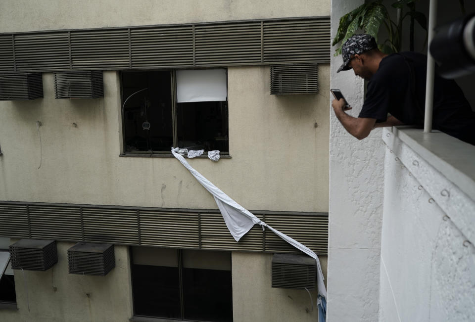 A man takes a photo of a rope made of bedsheets used to escape from the upper floor of the Badim Hospital, where a fire left at least 11 people dead, in Rio de Janeiro, Brazil, Friday, Sept. 13, 2019. The fire raced through the hospital forcing staff to wheel patients into the streets on beds or in wheelchairs. (AP Photo/Leo Correa)