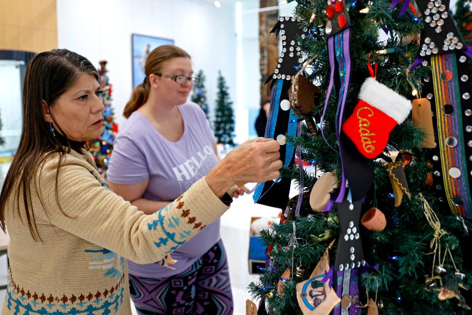 Yonavea Hawkins, left, and Cheyene Thom decorate the Caddo Nation tree for display before the annual Red Earth TreeFest at the Red Earth Art Center in the lobby of BancFirst Tower in Oklahoma City, Thursday, Nov. 9, 2023.