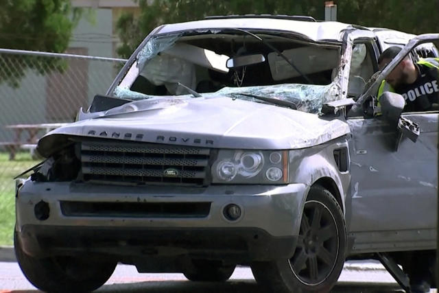 A law enforcement officer investigates a damaged vehicle 