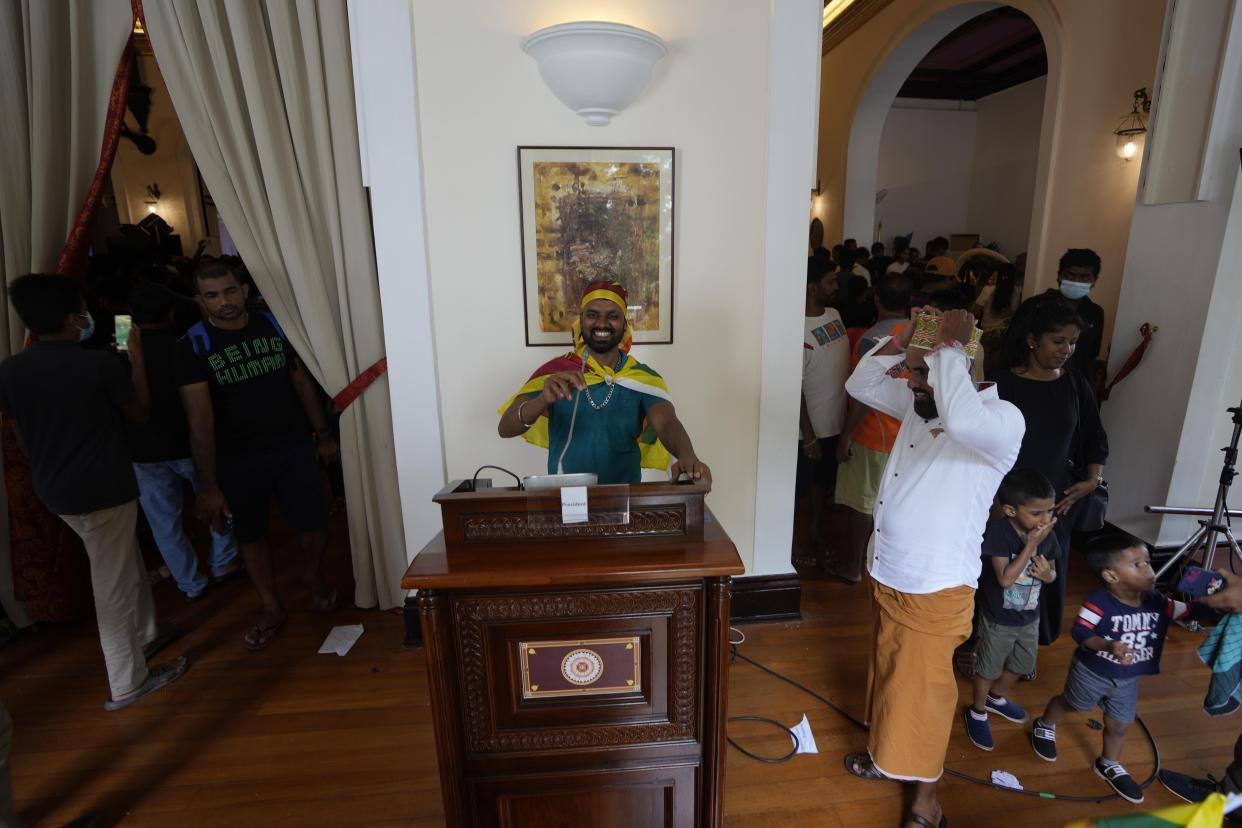 A protester pretends a address the nation using a podium at president's official residence a day after it was stormed in Colombo, Sri Lanka, Sunday, July 10, 2022. Sri Lanka’s opposition political parties will meet Sunday to agree on a new government a day after the country’s president and prime minister offered to resign in the country’s most chaotic day in months of political turmoil, with protesters storming both officials’ homes and setting fire to one of the buildings in a rage over the nation’s economic crisis. (AP Photo/Eranga Jayawardena)