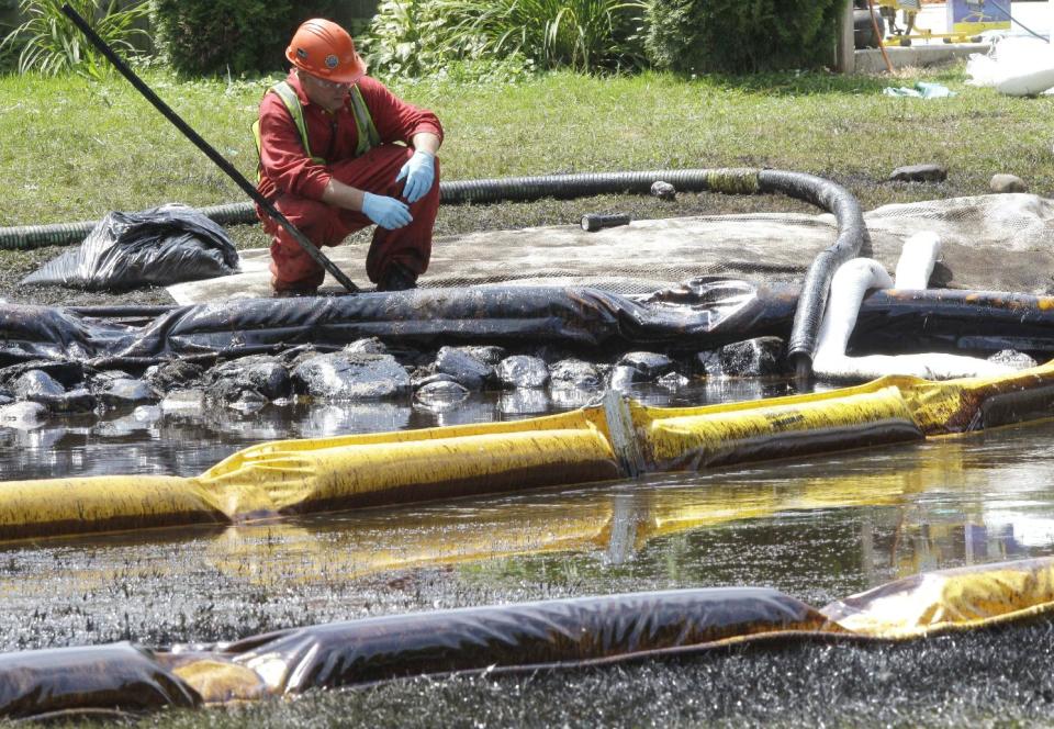 FILE - In this July 29, 2010, file photo, a worker monitors water in Talmadge Creek in Marshall Township, Mich., near the Kalamazoo River as oil from a ruptured pipeline, owned by Enbridge Inc., is attempted to be trapped by booms. Federal investigators are expected to present their findings Tuesday, July 10, 2012 on the likely cause of a pipeline rupture that spilled more than 800,000 gallons of crude oil into the river nearly two years ago. (AP Photo/Paul Sancya, File)