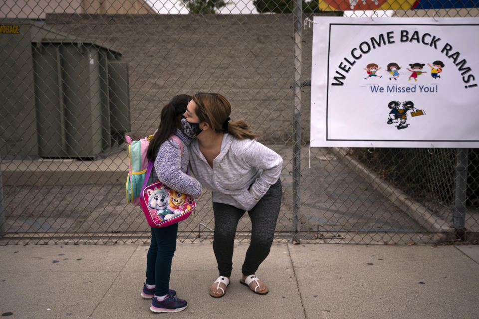 6-year-old Amanda Duran gets a hug from her mother, Lizette, on the first day of school at Heliotrope Elementary School in Maywood, Calif., Tuesday, April 13, 2021. More than a year after the pandemic forced all of California's schools to close classroom doors, some of the state's largest school districts are slowly beginning to reopen this week for in-person instruction.(AP Photo/Jae C. Hong)