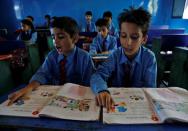 Village children attend their class at a government-run school near the Line of Control between India and Pakistan in Teetwal