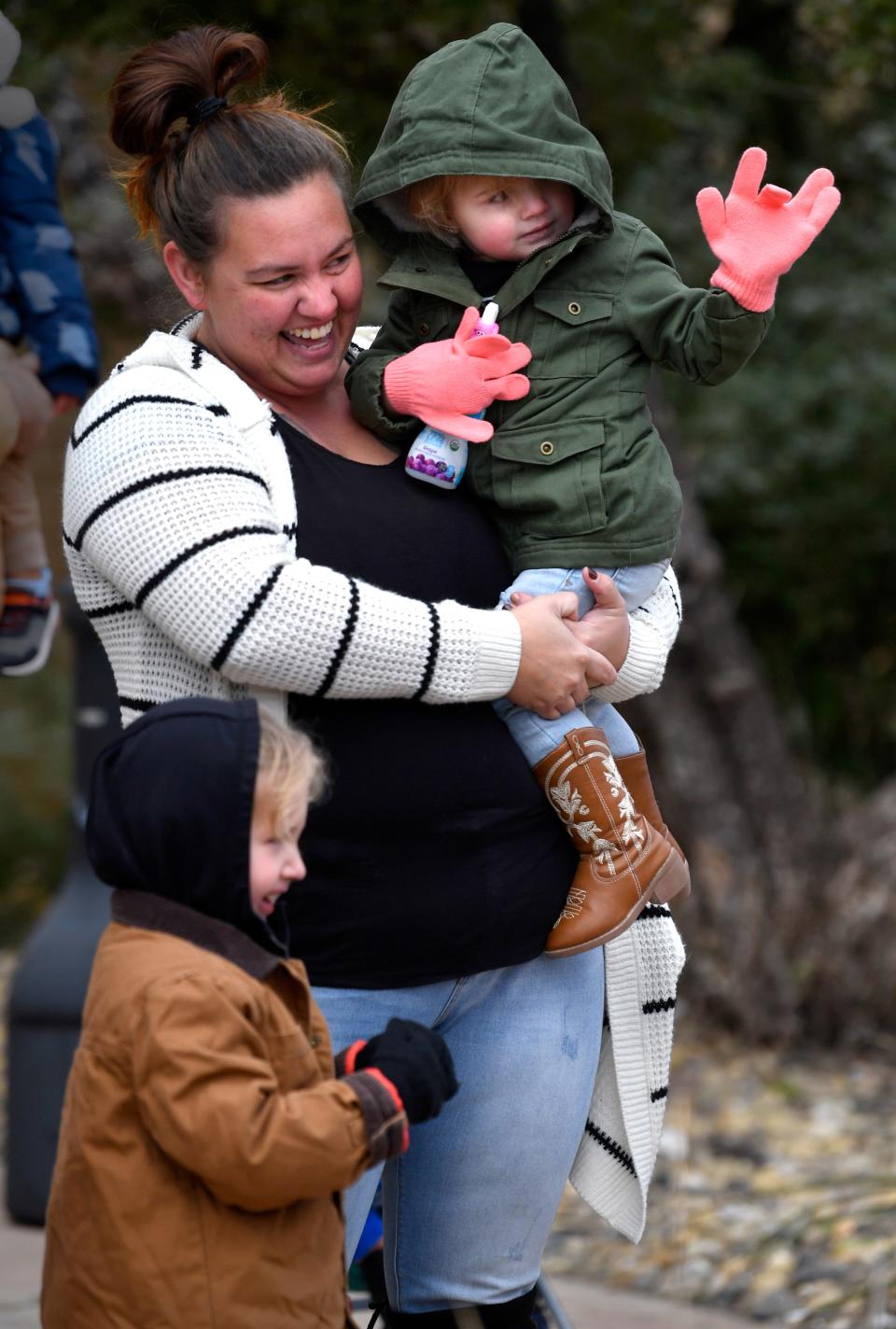 Emma Belsky, 2, waves from her mother's arms as Santa Claus arrives. Emma's brother Elliot, 5, stands close to their mother Brittney, who said they recently had moved to Abilene.