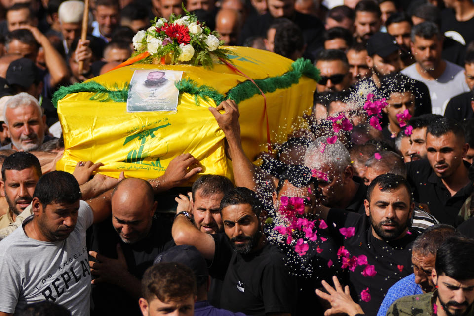 A woman throws rice and flowers as people carry the coffin of Hezbollah fighter, Bilal Nemr Rmeiti, who was killed by Israeli shelling, during his funeral procession in Majadel village, south Lebanon, Sunday, Oct. 22, 2023. (AP Photo/Hassan Ammar)