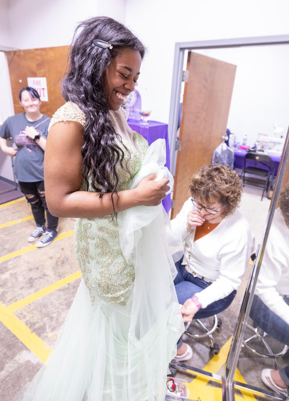 Washington High School senior Jaila Parker has her dress taken in by volunteer Amelia Ciccone at the Bear Hugs prom pop-up shop. It's the third year the group has opened its boutique to offer prom attendees a chance to pick out a free dress, shoes and accessories.