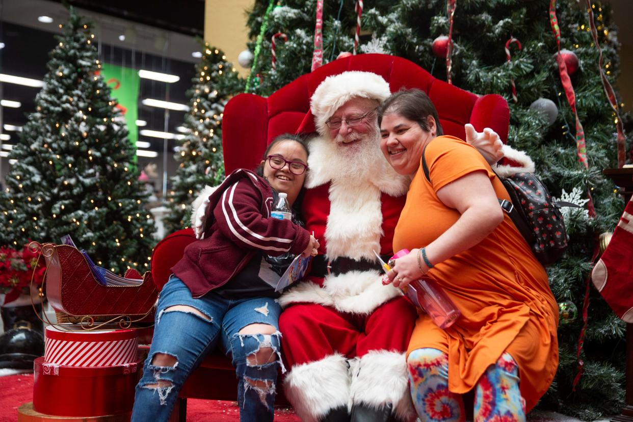 Becca, left, and Erin, right, from Angel Care of NM hug Santa Claus on Friday, Nov. 18, 2022, at Mesilla Valley Mall. Greg Scarboro comes to Las Cruces from Kentucky every year to play Santa. Scarboro says he loves coming to Las Cruces because, "the people (here) are just so warm... they really care about each other here." Mesilla Valley Mall says patrons can bring family and pets to take pictures with Santa from 11 a.m. to 7 p.m. Monday through Saturday and from noon to 5 p.m. Sunday through Dec. 24.