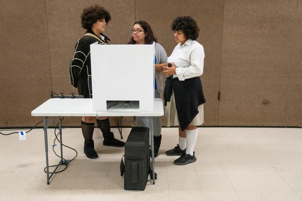 Maria Cancel, center, talks with her daughters Jaylene Cancel, 14, left, and Analise Wilson-Cancel, 16, about the issues as she votes at the Saint Stephens Community House in the Linden neighborhood of Columbus.