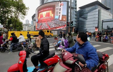 People watch a broadcast of Chinese President Xi Jinping delivering his speech during the opening of the 19th National Congress of the Communist Party of China, on a giant outdoor screen in Nanjing, Jiangsu province, China October 18, 2017. REUTERS/Stringer