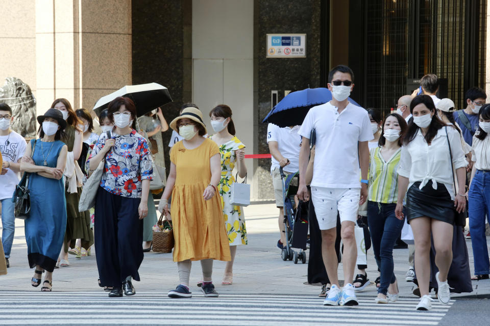 People wearing face masks to protect against the spread of the coronavirus walk on a street in Tokyo Saturday, July 24, 2021. (AP Photo/Koji Sasahara)