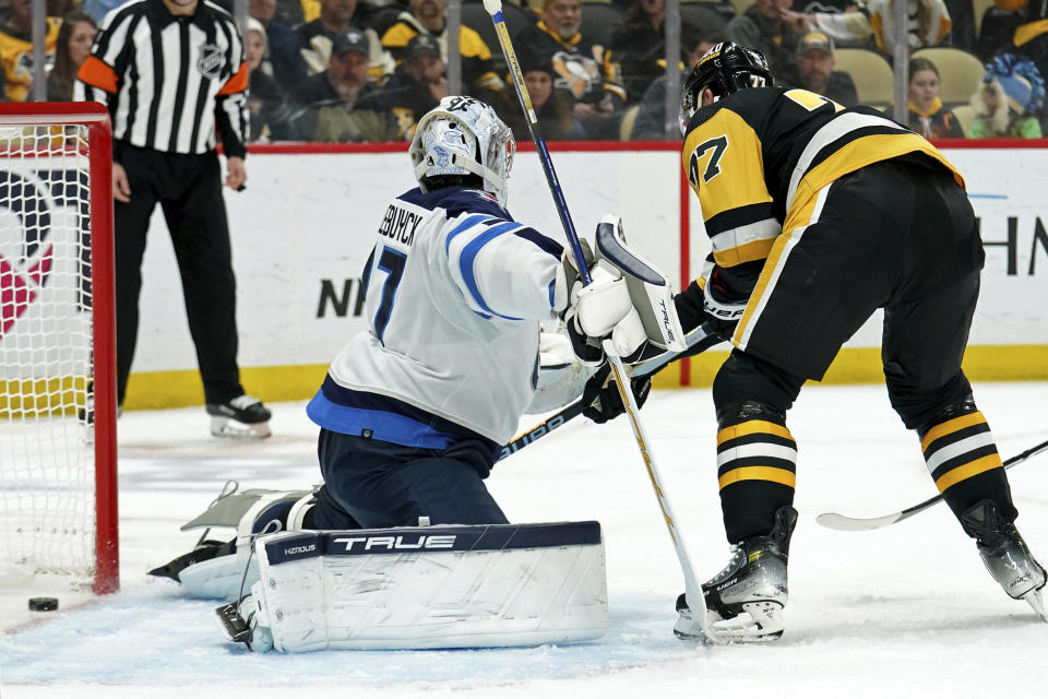 Pittsburgh Penguins' Jeff Carter (77) scores a goal on Winnipeg Jets goaltender Connor Hellebuyck (37) during the second period of an NHL hockey game, Tuesday, Feb. 6, 2024, in Pittsburgh. (AP Photo/Matt Freed)