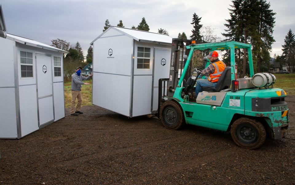 A crew moves one of six Pallet shelters into position near Roosevelt Boulevard in Eugene. The small modular structures can be set up within an hour.