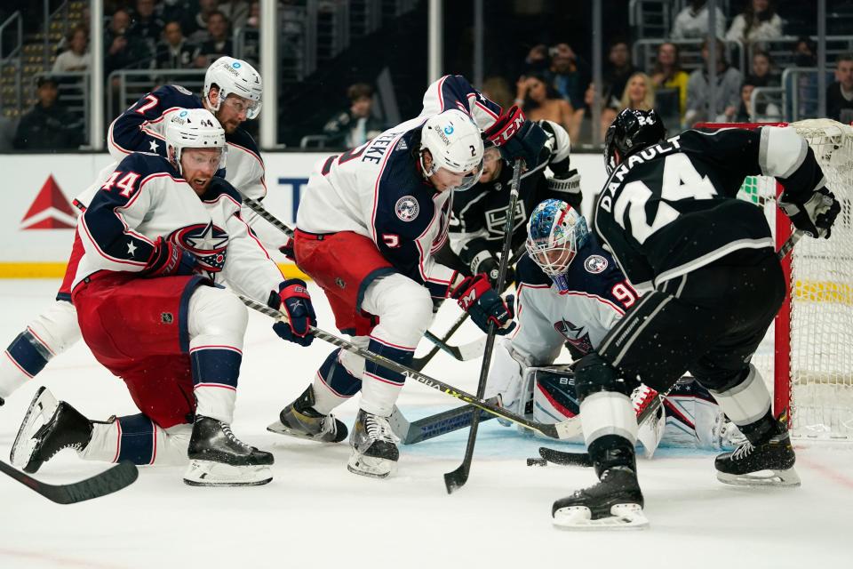 Los Angeles Kings center Phillip Danault (24) shoots against Columbus Blue Jackets defenseman Vladislav Gavrikov (44), defenseman Andrew Peeke (2) and goaltender Elvis Merzlikins (90) during the second period of an NHL hockey game Saturday, April 16, 2022, in Los Angeles. (AP Photo/Ashley Landis)