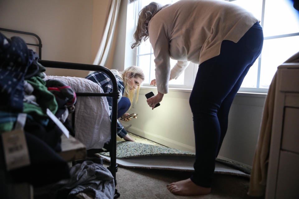 Kasey Wilson and friend Kendra Petro look for mold or wet spots under Wilson's bedroom window at the home she rents on the Dover Air Force Base.