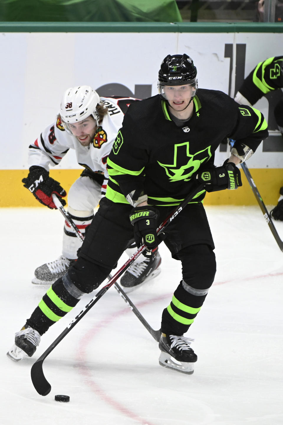 Dallas Stars defenseman John Klingberg (3) controls the puck in front of Chicago Blackhawks left wing Brandon Hagel (38) during the second period during an NHL hockey game in Dallas, Thursday, March 11, 2021. (AP Photo/Matt Strasen)
