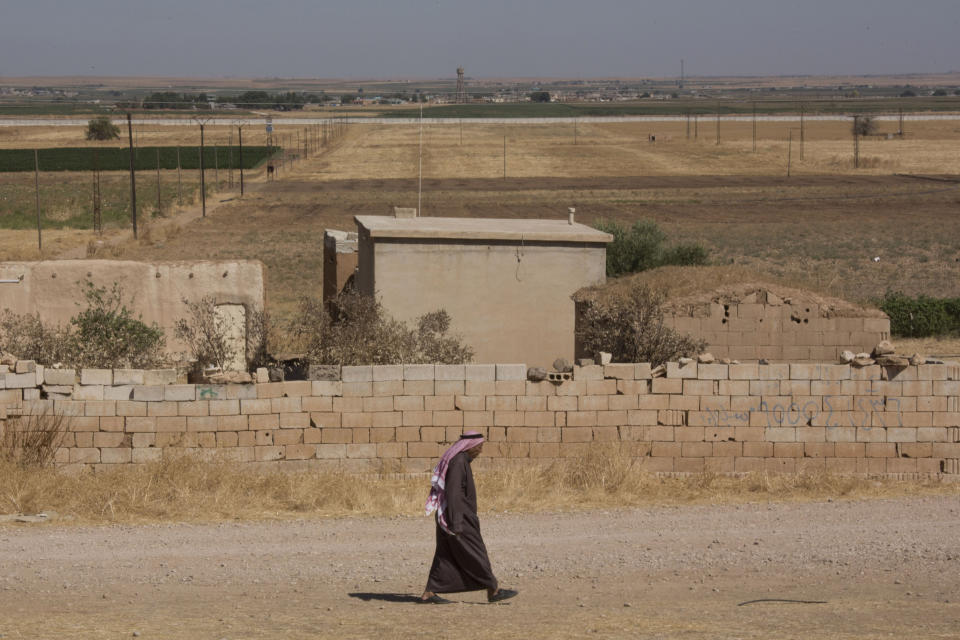 A man walks near a road where Turkish and American forces are conducting their first joint ground patrol in the so-called "safe zone" on the Syrian side of the border with Turkey, seen in the background, near Tal Abyad, Syria, Sunday, Sept. 8, 2019. Turkey hopes the buffer zone, which it says should be at least 30 kilometers (19 miles) deep, will keep Syrian Kurdish fighters, considered a threat by Turkey but U.S. allies in the fight against the Islamic State group, away from its border. (AP Photo/Maya Alleruzzo)