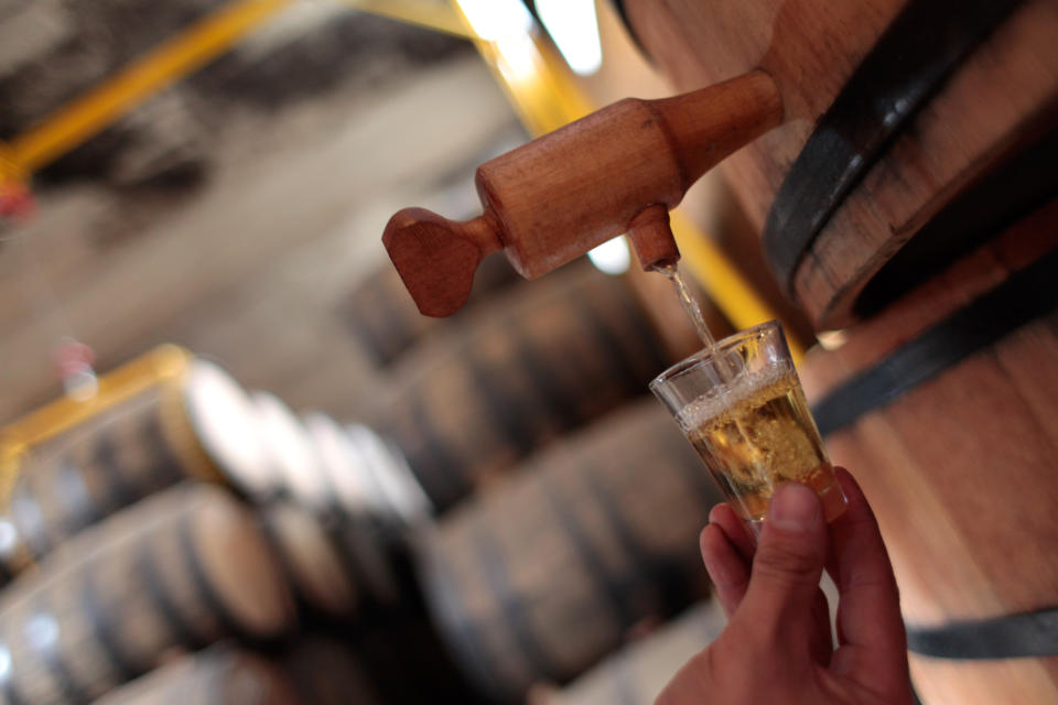 In this April 5, 2013 photo, a man fills a glass with cachaca, Brazil's national spirit, in a cellar at the Alambique Cambeba in Alexania, Goias state, Brazil. With Brazil's cool factor rising as the country gears up for next year's soccer World Cup and the 2016 Olympics, producers of the national spirit cachaca hope the hype will push up sales as well. (AP Photo/Eraldo Peres)