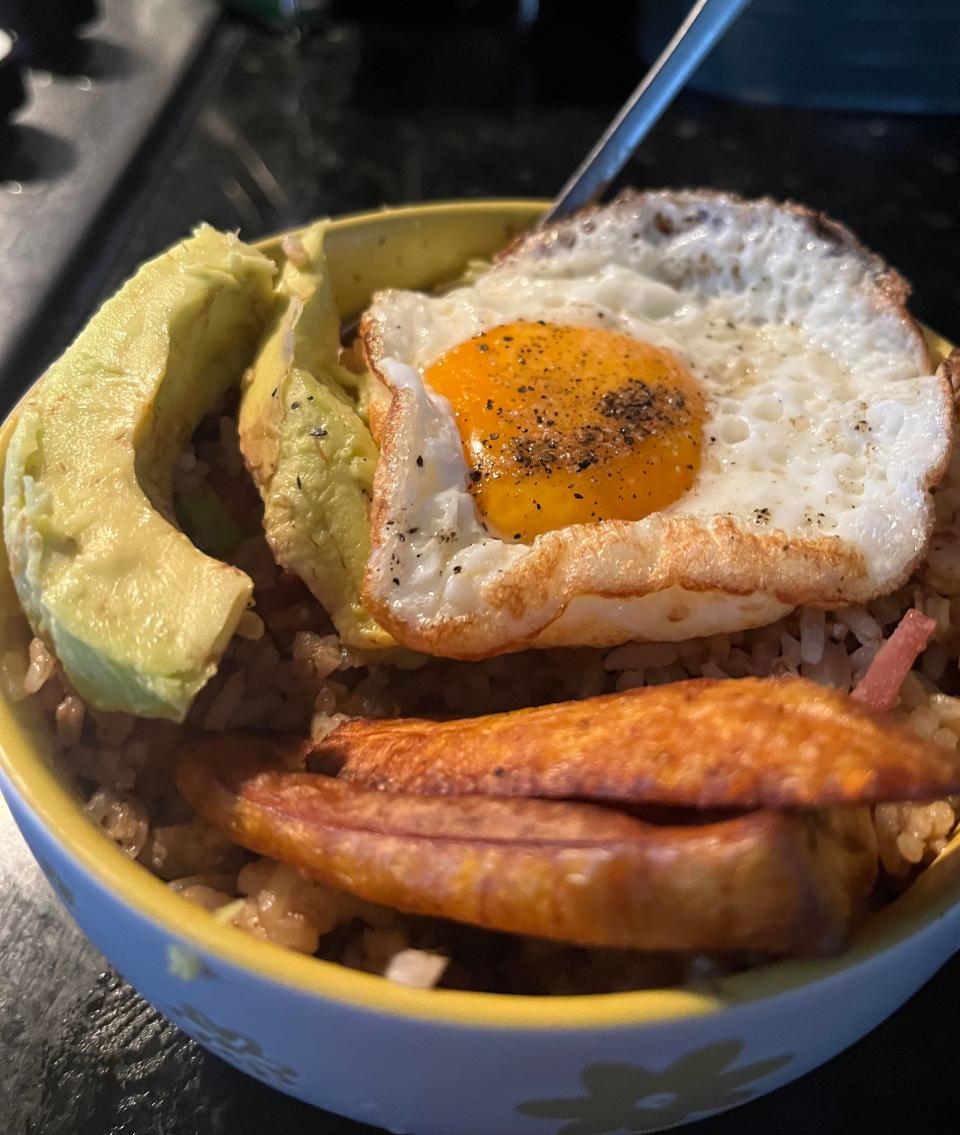 Bowl with rice, a fried egg on top, avocado slices, and fried plantains on the side