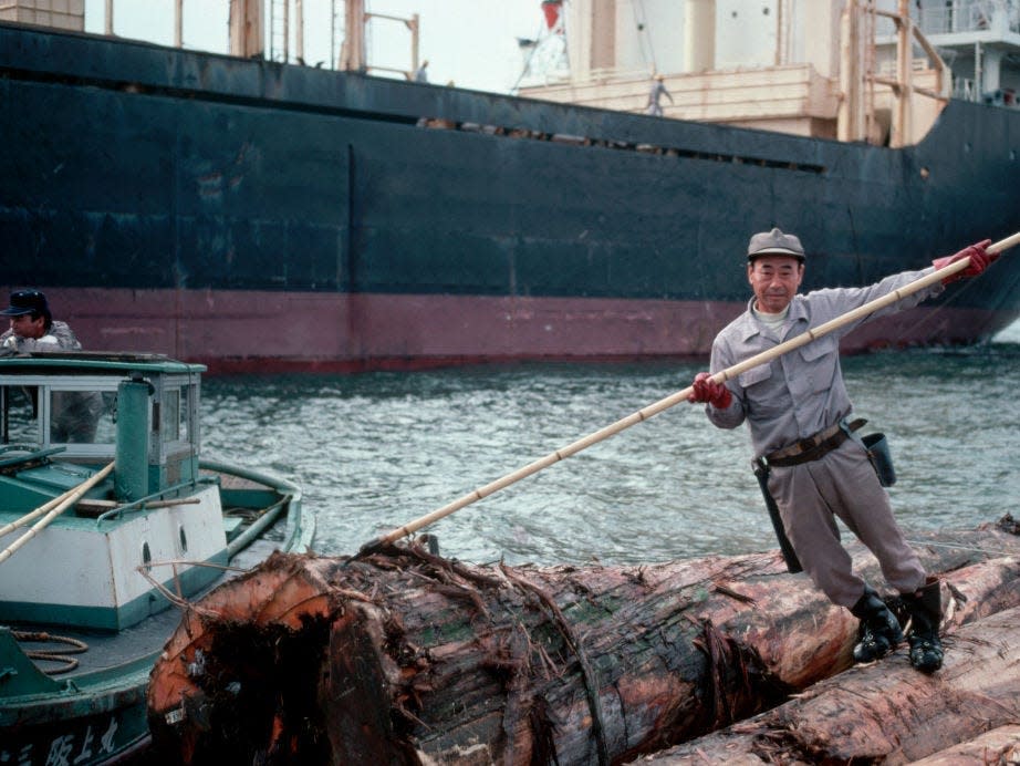 A man unloads American logs from a cargo ship in Osaka, Japan in 1983