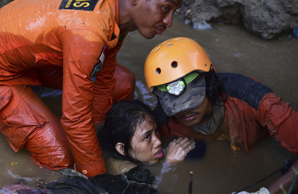 In this Sunday, Sept. 30, 2018, file photo, rescuers try to rescue a 15-year old earthquake victim Nurul Istikharah from flood water in her damaged house following earthquakes and tsunami in Palu, Central Sulawesi, Indonesia. (AP Photo/Arimacs Wilander, File)