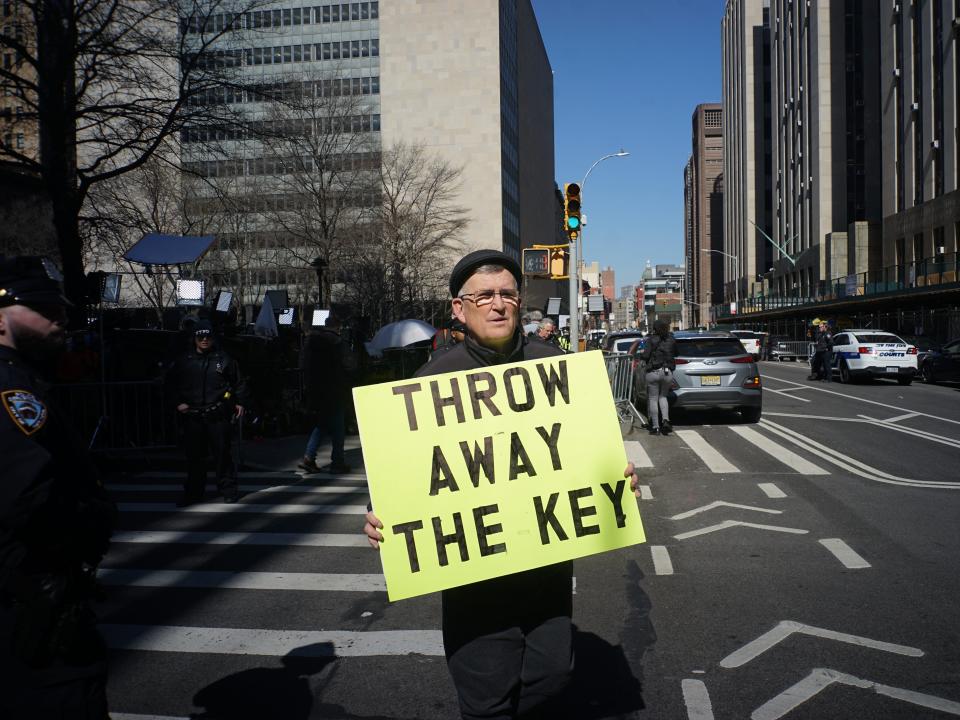 A man holds up a sign protesting Pres. Trump outside of Manhattan Criminal Court on March 21, 2023.