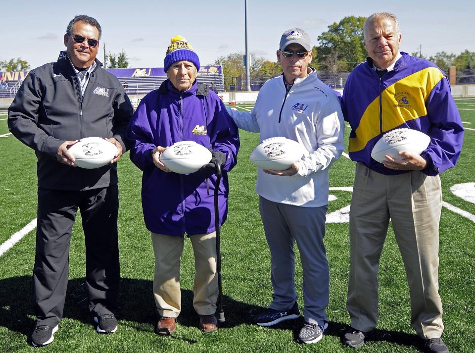 From left to right, assistant coach John Saccomen, former head coach Fred Martinelli, head coach Lee Owens and former head coach Gary Keller pose with game balls commemorating the Ashland University football program’s 500th victory, which came on Sept. 28, 2019 against Northwood. The photo was taken Oct. 12, 2019 before the game against Davenport.