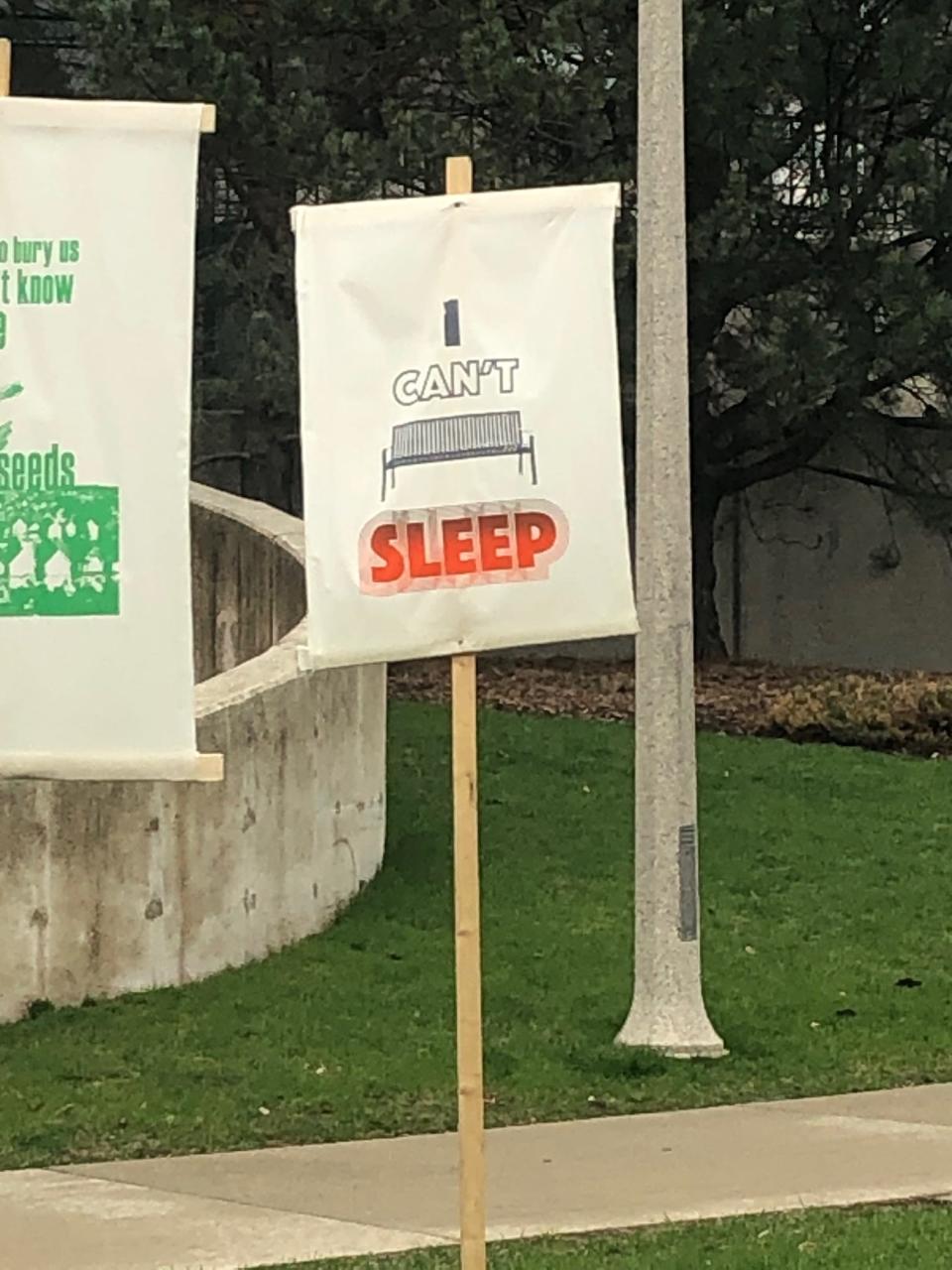 Signs in support of Dontre Hamilton are temporarily staked into the ground at the unveiling of a memorial bench for Hamilton Saturday at Red Arrow Park. A Milwaukee police officer fatally shot Hamilton eight years ago to the day.