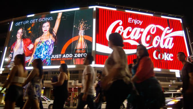 Sydney, Australia - March 22, 2014: A large group of people walk past two large neon Coca-Cola billboards on Kings Cross at night.