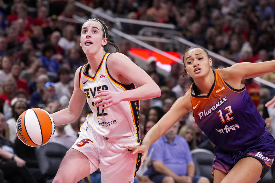 Indiana Fever guard Caitlin Clark (22) drives past Phoenix Mercury's Celeste Taylor (12) in the second half of a WNBA basketball game in Indianapolis, Friday, July 12, 2024. (AP Photo/Michael Conroy)