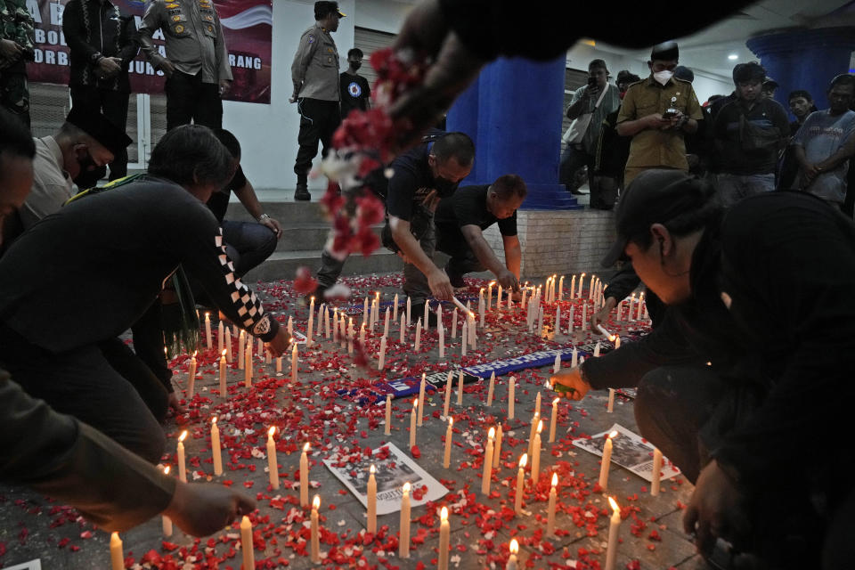 Soccer fans light candles and sprinkle flowers during a vigil for the victims of Saturday's stampede, in Tangerang, Indonesia, Tuesday, Oct. 4, 2022. Police firing tear gas inside a stadium in East Java on Saturday in an attempt to stop violence after an Indonesian soccer match triggered a disastrous crush of fans making a panicked, chaotic run for the exits, leaving at a number of people dead, most of them trampled upon or suffocated. (AP Photo/Dita Alangkara)