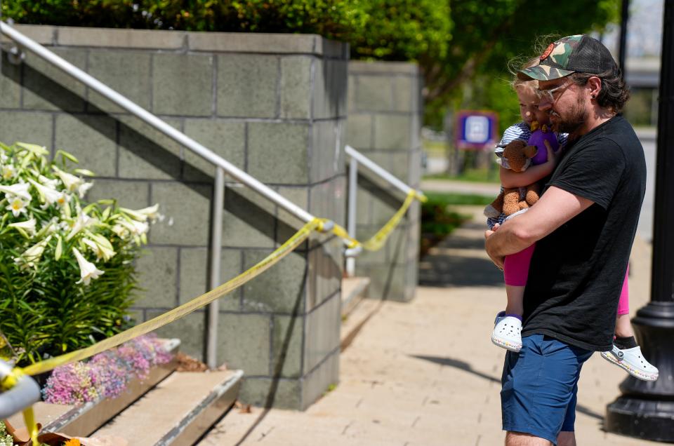 Kevin Canterbury, brought his daughter, Lenya, four-years-old, to visit the memorial at Old National Bank Tuesday, April 11, 2023 after a mass shooting Monday morning that left six dead, including the shooter, and another 8 injured. Canterbury, pastor of Rock Vineyard Church in the Highlands, said it's important to have a conversation with his children about the events that took place.  He also said his church held a prayer vigil Monday night. 