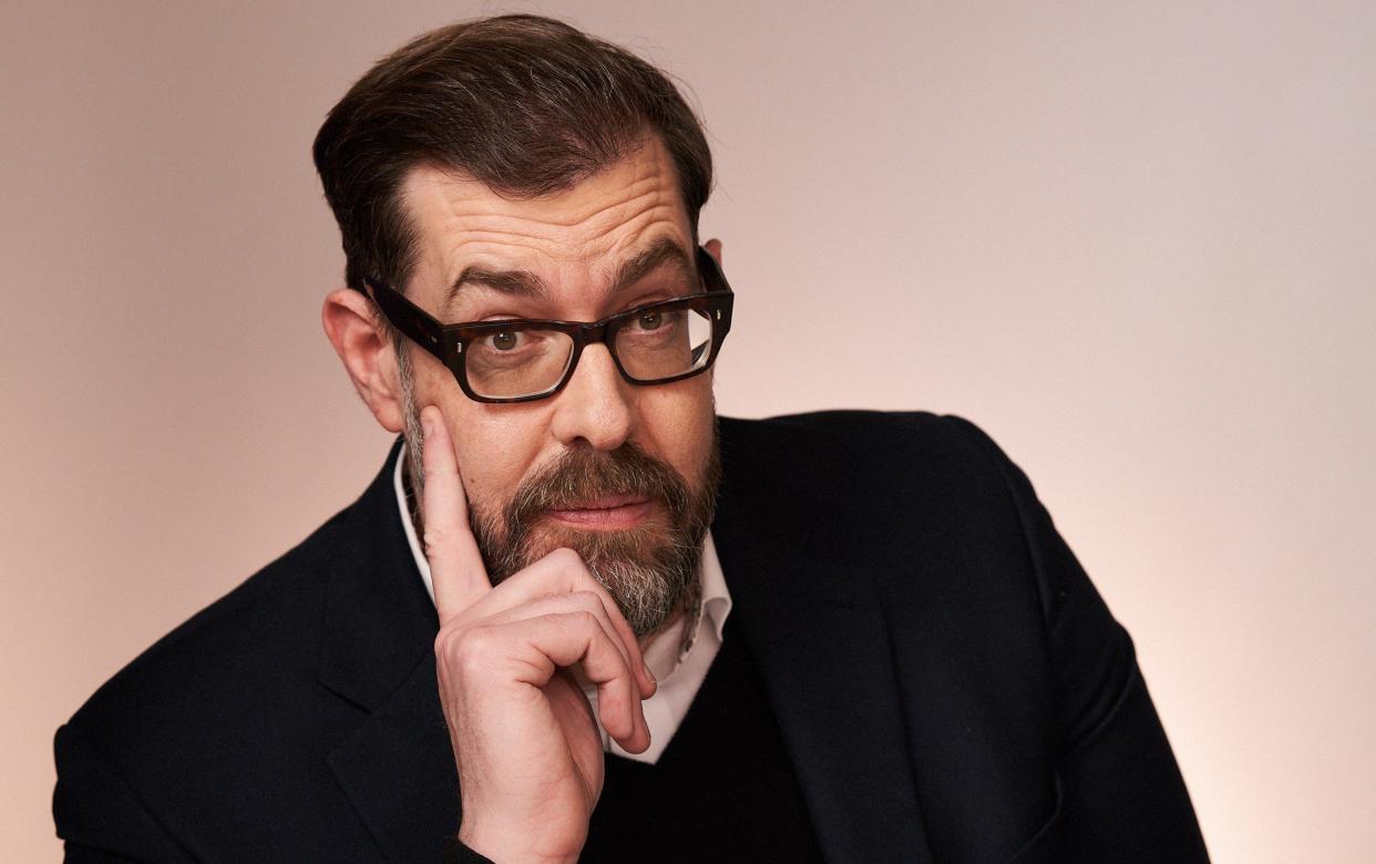 Richard Osman gives a wry smile as he wears his usual heavy-framed spectacles