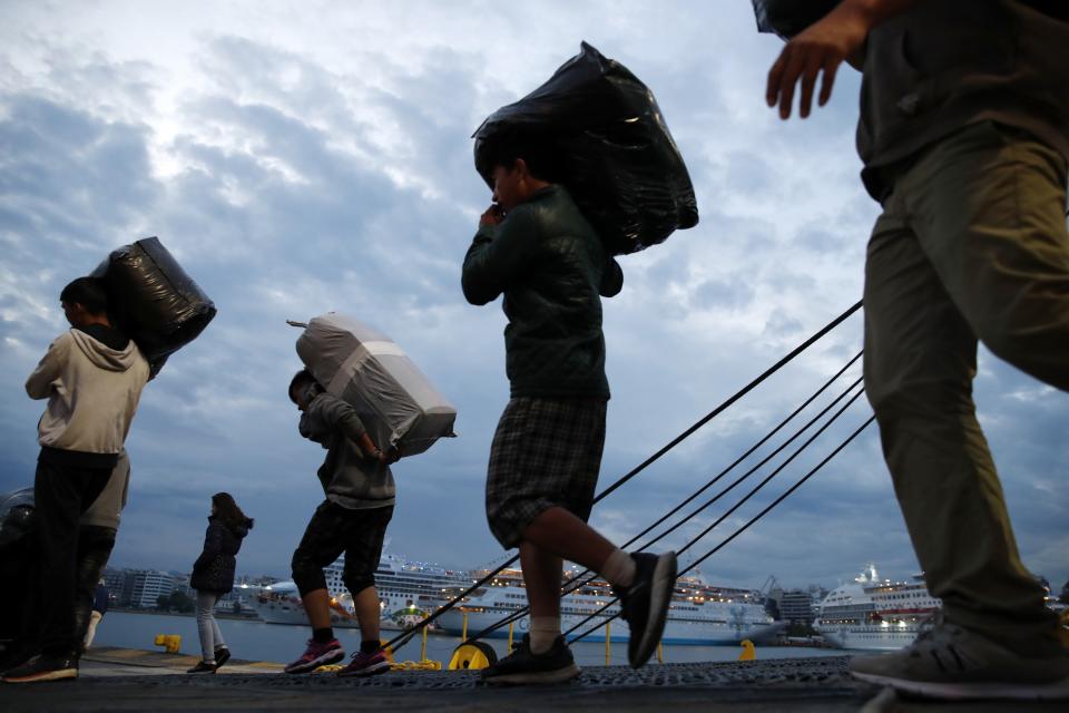 Migrants carry their belongings as they arrive from Lesbos island to the port of Piraeus, near Athens, Monday Oct. 7, 2019. In the last 24 hours 668 refugees and migrants have been transferred to mainland Greece from five Greek islands as authorities have accelerated efforts to ease over crowding in the camps. (AP Photo/Thanassis Stavrakis)