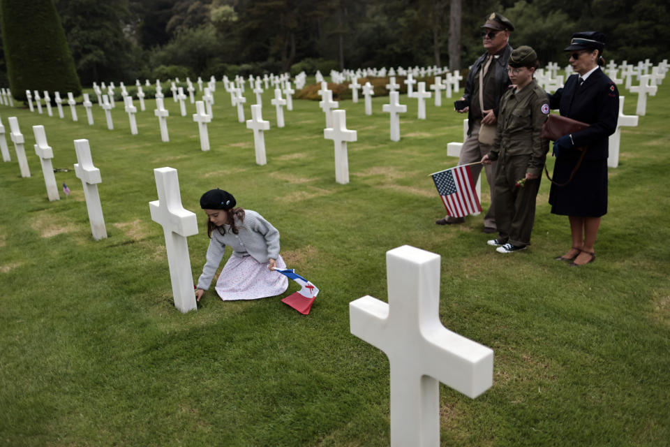 Alice, let, puts a flower, as family members Remy, Dalma and Sylvie, from left to right, look on, in the 1944 headstones of the US cemetery of Colleville-sur-Mer, Normandy, Saturday, June, 4, 2022. Several ceremonies will take place to commemorate the 78th anniversary of D-Day that led to the liberation of France and Europe from the German occupation. (AP Photo/Jeremias Gonzales)