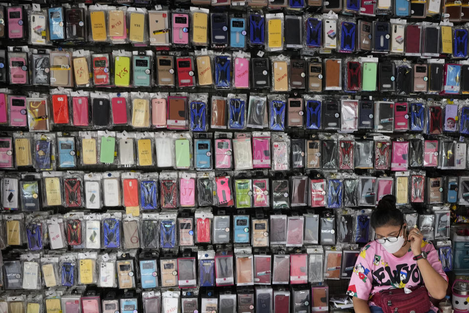 A mobile phone case vendor wearing a protective mask to help curb the spread of the coronavirus waits for customers in Bangkok, Thailand, Tuesday, Sept. 14, 2021. (AP Photo/Sakchai Lalit)