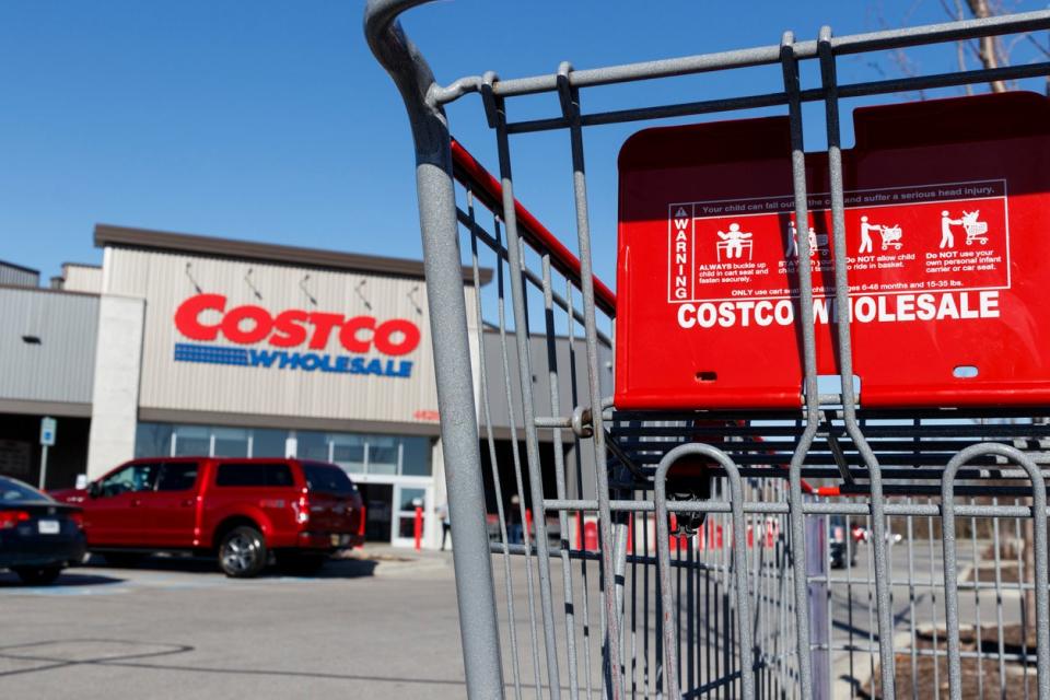 Exterior of a Costco warehouse with a shopping cart in the foreground.
